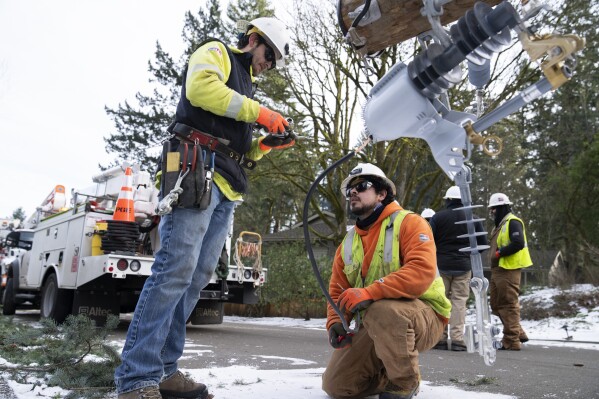 Workers from PGE work on restoring power to the area after a storm on Tuesday, Jan. 16, 2024, in Lake Oswego, Ore. (AP Photo/Jenny Kane)