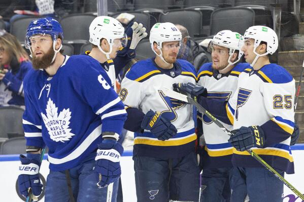 St. Louis Blues' Pavel Buchnevich, center, celebrates with teammates after scoring as Toronto Maple Leafs' Jake Muzzin, left, skates past during first-period NHL hockey game action in Toronto, Saturday, Feb. 19, 2022. (Chris Young/The Canadian Press via AP)