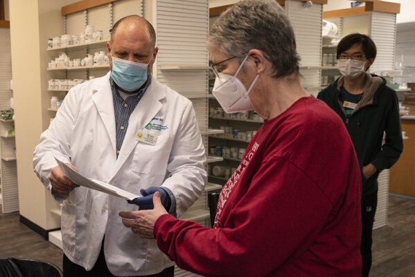Pharmacist Brian Meyer goes over paperwork with Kay Ketzenberger after giving her the first dose of the Moderna COVID-19 vaccine on Tuesday, Jan. 5, 2021 at Sunflower Pharmacy in Odessa, Texas. Sunflower Pharmacy is the first privately owned pharmacy in Odessa given to permission to distribute the vaccine. (Eli Hartman/Odessa American via AP)