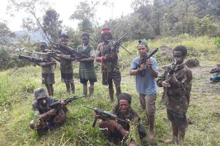 In this photo taken in May 2019, and released by the West Papua Liberation Army-Free Papua Organization, men and boys from the West Papua Liberation Army pose with weapons in the Nduga region of the central highlands, Papua province, Indonesia. (West Papua Liberation Army-Free Papua Organization via AP)