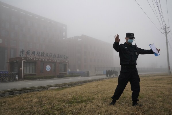 FILE - A security person moves journalists away from the Wuhan Institute of Virology after a World Health Organization team arrived for a field visit in Wuhan in China's Hubei province on Feb. 3, 2021. The hunt for COVID-19 origins has gone dark in China. An AP investigation drawing on thousands of pages of undisclosed emails and documents and dozens of interviews found feuding officials and fear of blame ended meaningful Chinese and international efforts to trace the virus almost as soon as they began, despite years of public statements to the contrary. (AP Photo/Ng Han Guan, File)