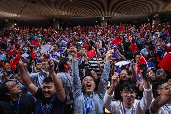 The crowd cheers with Chinese flags during the opening ceremony of the 19th Asian Games in Hangzhou, China, Saturday, Sept. 23, 2023. (AP Photo/Louise Delmotte)