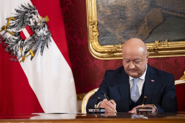 Chancellor Christian Stocker signs papers during the swearing-in ceremony of the Federal Government in the presidential office at the Hofburg Palace, in Vienna, Austria, Monday, March 3, 2025. (AP Photo/Denes Erdos)