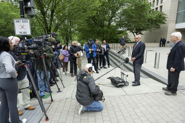 U.S. Institute of Peace (USIP) acting President George Moose, second from right, and USIP acting Counsel George Foote, right, to talk to the press outside the Institute, Wednesday, May 21, 2025 in Washington. (AP Photo/Kevin Wolf)