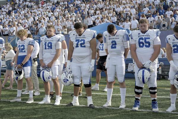 Members of the Indiana State NCAA college football team and fans observe a moment of silence for teammates Caleb VanHooser and Christian Eubanks before the start of the Sycamores' game against North Alabama at Memorial Stadium in Terre Haute, Ind., on Sept. 1, 2022. (Joseph C. Garza/The Tribune-Star via AP)