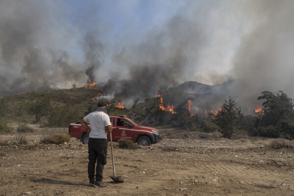 A man watches the fire burning a forest in Vati village, on the Aegean Sea island of Rhodes, southeastern Greece, on July 25, 2023. (AP Photo/Petros Giannakouris)
