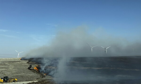 In this image provided by Texas A&M Forest Service, heavy equipment works to contain the Juliet Pass Fire in Armstrong County, Texas, on Monday, Feb. 26, 2024. (Chloe Lake/Texas A&M Forest Service via AP)