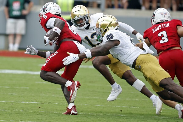 North Carolina State's Julian Gray (8) tries to avoid the tackle of Notre Dame's DJ Brown, right, and Thomas Harper (13) during the first half of an NCAA college football game in Raleigh, N.C., Saturday, Sept. 9, 2023. (AP Photo/Karl B DeBlaker)