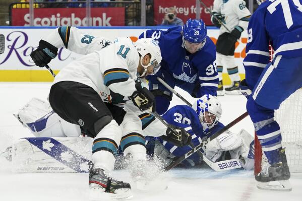 Toronto Maple Leafs goaltender Michael Hutchinson (30) covers the puck as San Jose Sharks' Andrew Cogliano (11) and Matt Nieto (83) look for a rebound during the third period of an NHL hockey game Friday, Oct. 22, 2021, in Toronto. (Evan Buhler/The Canadian Press via AP)