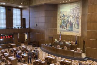 A handful of senators talk on the floor of the Oregon State Senate on Monday, Sept. 20, 2021, as the Oregon Legislature conducted a special session to consider redistricting. The aim of the session is to pass new legislative and congressional district maps which the state will use for elections. (AP Photo/Andrew Selsky)