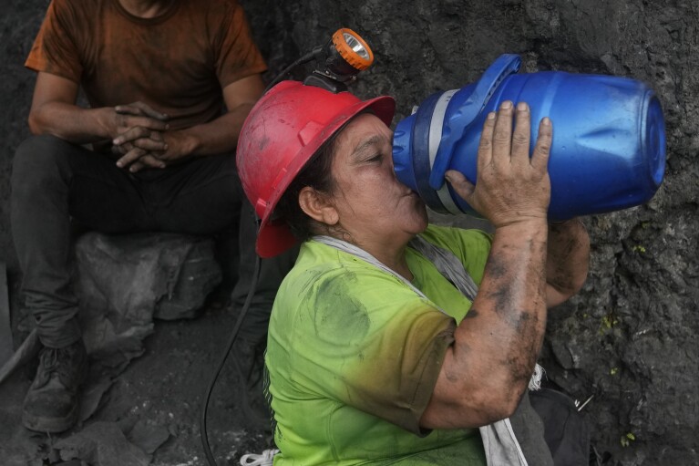 Emerald miner Yaneth Forero, 52, hydrates during a break outside an informal mine near the town of Coscuez, Colombia, Thursday, Feb. 29, 2024. Workers at small, unregulated mines like Forero, who still use dynamite sticks to open tunnels, have a slim chance of finding the emeralds that can change someone’s destiny. (AP Photo/Fernando Vergara)