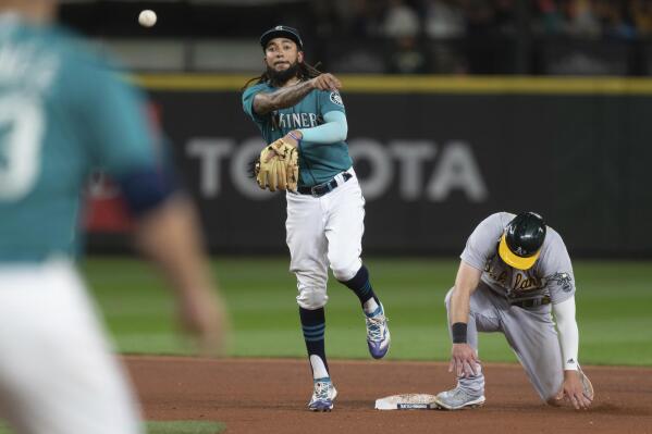 Seattle Mariners shortstop J.P. Crawford turns a double play after forcing out Oakland Athletics' Seth Brown at second base on a ball hit by Conner Capel during the seventh inning of a baseball game Friday, Sept. 30, 2022, in Seattle. (AP Photo/Stephen Brashear)