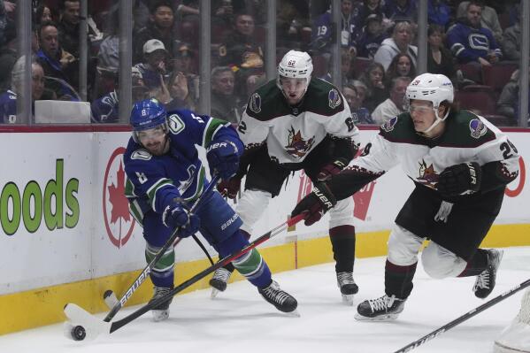 Vancouver Canucks' Conor Garland (8) vies for the puck against Arizona Coyotes' Barrett Hayton (29) as Janis Moser (62) watches during the first period of an NHL hockey game Thursday, April 14, 2022, in Vancouver, British Columbia. (Darryl Dyck/The Canadian Press via AP)