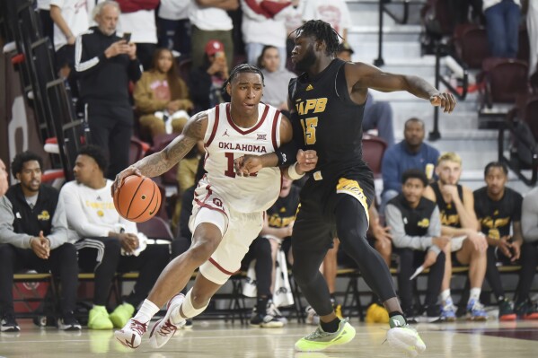 Oklahoma forward Jalon Moore, left, pushes past Arkansas-Pine Bluff forward Ismael Plet, right, during the first half of an NCAA college basketball game in Norman, Okla., Thursday, Nov. 30, 2023. (AP Photo/Kyle Phillips)