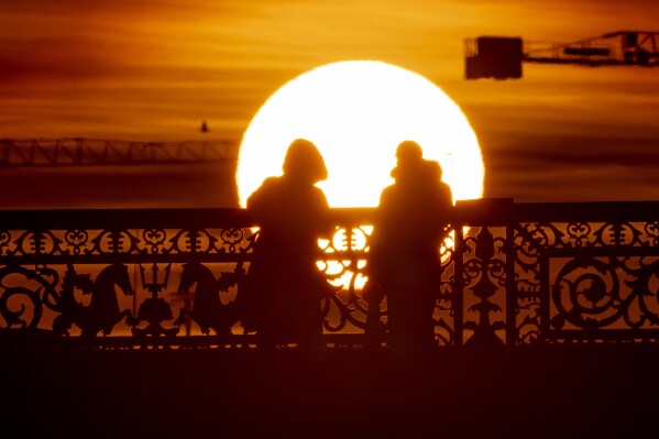 A couple stand on a bridge during sunset in St. Petersburg, Russia, Thursday, Feb. 20, 2025. (AP Photo/Dmitri Lovetsky)