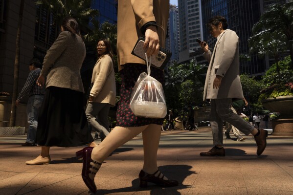 A pedestrian carries takeaway food plastic bag in Hong Kong, Wednesday, March 13, 2024. Hong Kong has long been a major producer and consumer of great food, and a great amount of plastic and Styrofoam to go with it. That’s going to change as new legislation aiming to stop the sale and distribution of Styrofoam products and single-use plastic cutlery went into effect on Monday, April 22, 2024. (AP Photo/Louise Delmotte)