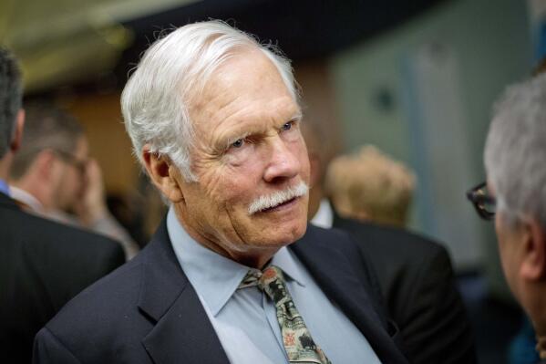 FILE - In this Dec. 6, 2013, file photo, Ted Turner talks with guests at the Captain Planet Foundation benefit gala in Atlanta. Media mogul and billionaire bison rancher Turner is donating an 80,000-acre ranch he owns in western Nebraska to his own nonprofit agriculture ecosystem research institute and says he might do the same with four other ranches in Nebraska's Sand Hills. But he'll continue to pay taxes on the land, much to the relief of local officials and Nebraska leaders, the Omaha World-Herald reported Thursday, July 8, 2021. (AP Photo/David Goldman, File)