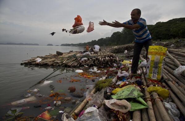FILE - A Hindu devotee throws flowers and plastic bags into river Brahmaputra in Gauhati, India, Wednesday, Oct. 9, 2019. Negotiators from around the world gather at UNESCO in Paris on Monday, May 29, 2023, for a second round of talks aiming toward a global treaty on fighting plastic pollution in 2024. (AP Photo/Anupam Nath, File)