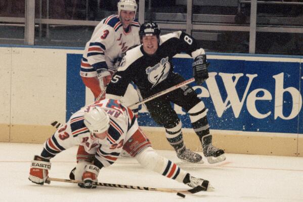 FILE - New York Rangers Tony Amonte (33) hits the ice while being pursued by Tampa Bay Lightning player Petr Klima (85) as Rangers' James Patrick (3) looks on during the first period of an NHL hockey game at Madison Square Garden in New York, Oct. 7, 1993. Czech forward Petr Klima, a Stanley Cup winner with the Edmonton Oilers in 1990, has died. He was 58. Klima died Thursday, May 4, 2023, in the Czech Republic. The cause of death was not given. (AP Photo/Mike Albans, File)