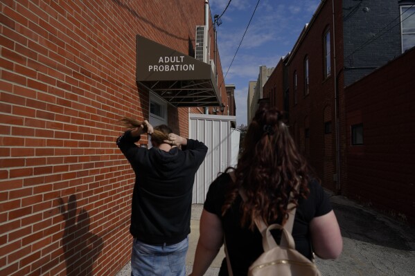 Jesse Johnson of the Family Resource Center, right, walks with client Tyler Baker to the Hancock County Adult Probation office for a random drug test in Findlay, Ohio, Thursday, Oct. 12, 2023. Earlier this year, Johnson started a job with the Family Resource Center, the same organization that employed the peer support worker who was so instrumental in her own early recovery. (AP Photo/Carolyn Kaster)