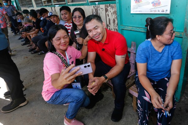 In this photo provided by Team Pacquiao, Filipino boxing hero and former senator Manny Pacquiao has his picture taken with a voter as he arrives to cast his vote at Kiamba Central Elementary School in Kiamba, Sarangani province, southern Philippines, Monday, May 12, 2025. (Wendell Alinea/Team Pacquiao via AP)
