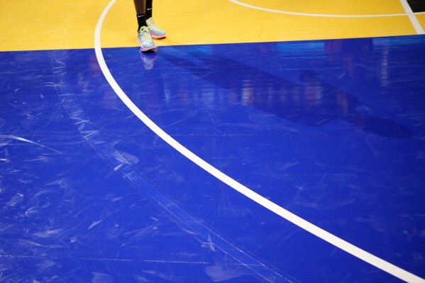 A faint arc, left, where the 3-point line was incorrectly painted on the floor, can still be seen outside the actual 3-point line, during the second half of an NBA basketball in-season tournament game between the Dallas Mavericks and Denver Nuggets on Friday, Nov. 3, 2023, in Denver. (AP Photo/David Zalubowski)