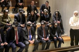 
              U.S. National Security Adviser John Bolton, seated front row forth from left, participates in a virtual reality demonstration at the Western Wall on Sunday, Jan. 6, 2019, in Jerusalem. U.S. Ambassador to Israel David Friedman and Israeli Ambassador to the U.S. Ron Dermer are sitting alongside. (AP Photo/Zeke Miller)
            