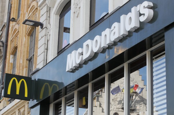 FILE - A French and a European flags are reflected in the shop window of a McDonald's restaurant in Lille, northern France, Thursday, June 16, 2022 . McDonald’s will become the title sponsor of the French soccer league from July for the next three seasons, the league said on Thursday, March 21, 2024. (AP Photo/Michel Spingler, File)