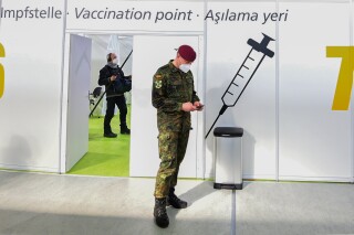 FILE - A soldier of the German Armed Forces Bundeswehr stands inside a new vaccination centre at the former Tempelhof airport in Berlin, Germany, before its opening on Monday, March 8, 2021. Germany has scrapped a requirement for its military servicepeople to be vaccinated against COVID-19. Members of the German military, the Bundeswehr, are required to get vaccinations against a number of diseases — including measles, mumps and flu. COVID-19 was added to the list in November 2021, meaning that anyone who refused to get vaccinated against it could face disciplinary measures. (Tobias Schwarz / Pool via AP, File)