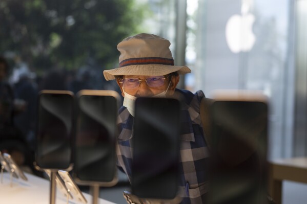 File - A man looks at the Apple's new iPhone 15 models on the first day of sales at an Apple Store in Los Angeles on Sept. 22, 2023. On Tuesday, the Commerce Department releases U.S. retail sales data for September. (AP Photo/Jae C. Hong, File)