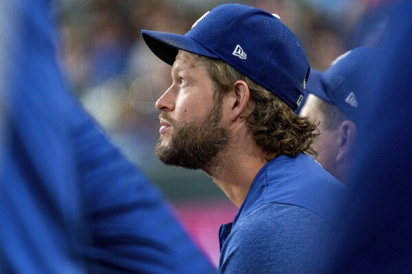 Los Angeles Dodgers starting pitcher Clayton Kershaw, who is on the 15-day injured list, sits in the dugout during the ninth inning of a baseball game against the Texas Rangers, Saturday, July 22, 2023, in Arlington, Texas. (AP Photo/Jeffrey McWhorter)