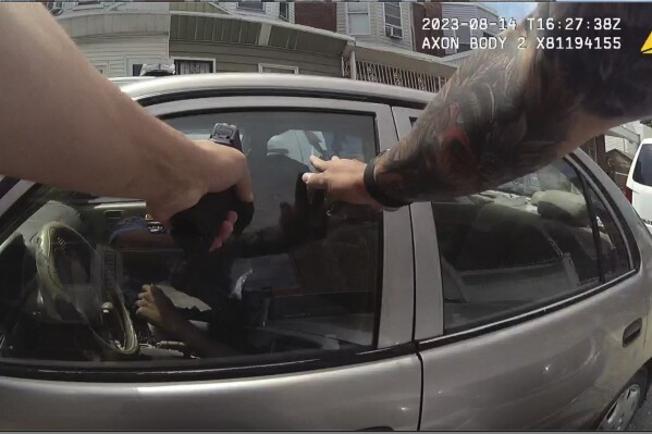 FILE - This screen grab taken from police body cam video shows Philadelphia Police Officer Mark Dial with his weapon drawn at Eddie Irizarry on Aug. 14, 2023 in Philadelphia. A judge has reinstated all charges, including a murder count, against the former officer who shot and killed the driver through a rolled-up car window — a confrontation police initially described as the officer shooting the driver after he lunged at him with a knife outside the car. Common Pleas Court Judge Lillian Ransom ruled Wednesday, Oct. 25, 2023 after a hearing that the facts of the case should be established at a trial. (Philadelphia Police Department via AP, File)