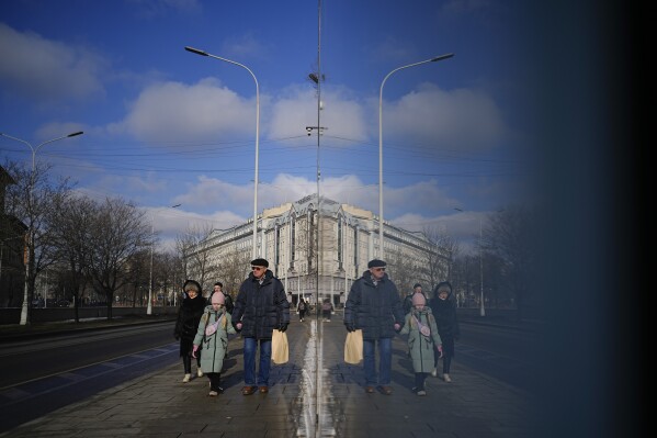 People walk reflecting in a shop window in Moscow, Russia, Tuesday, Feb. 18, 2025. (AP Photo/Pavel Bednyakov)