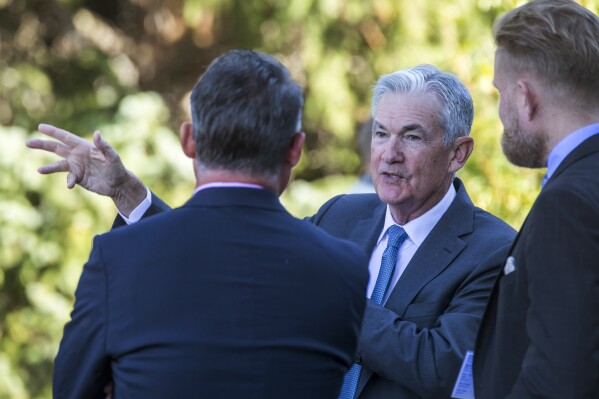 File - Federal Reserve Chair Jerome Powell, center, talks with attendees of the central bank's annual symposium at Jackson Lake Lodge in Grand Teton National Park, Aug. 26, 2022. in Moran, Wyo. As Powell returns to Jackson Hole this week, the U.S. economy's resilience has raised the prospect that the Fed will need to keep its key rate higher for longer than had been expected. (AP Photo/Amber Baesler, File)