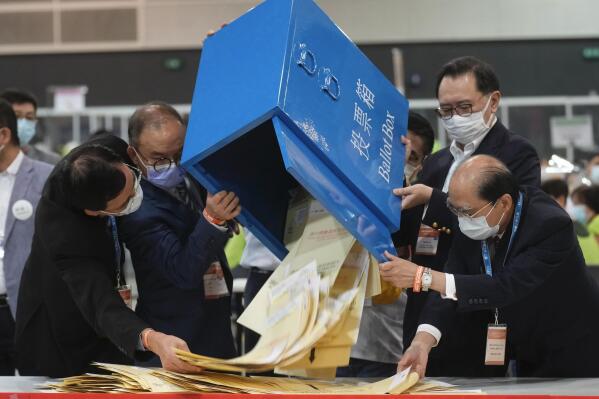 Erick Tsang, second left, Secretary for Constitutional and Mainland Affairs Bureau, helps officials pour out ballots from a box at a counting center in Hong Kong, Sunday, Sept. 19, 2021. Select Hong Kong residents voted for members of the Election Committee that will choose the city's leader in the first polls Sunday following reforms meant to ensure candidates with Beijing loyalty. (AP Photo/Vincent Yu)