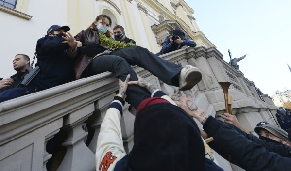 Members of a far-right organization and police remove women from a church where they were protesting church support for tightening Poland's already restrictive abortion law in Warsaw, Poland, Sunday, Oct. 25, 2020. Poland constitutional court issued a ruling on Thursday that further restricts abortion rights in Poland, triggering four straight days of protests across Poland.(AP Photo/Czarek Sokolowski)