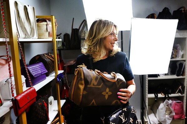 Deborah Mayer holds one of the luxury handbags she sells on TikTok, Wednesday, March 21, 2024, in Freehold, N.J. Mayer has sold new and pre-owned handbags and other designer goods out of her New Jersey home for 16 years. Early last year, TikTok recruited her business for the live component of TikTok Shop. (AP Photo/Noah K. Murray)