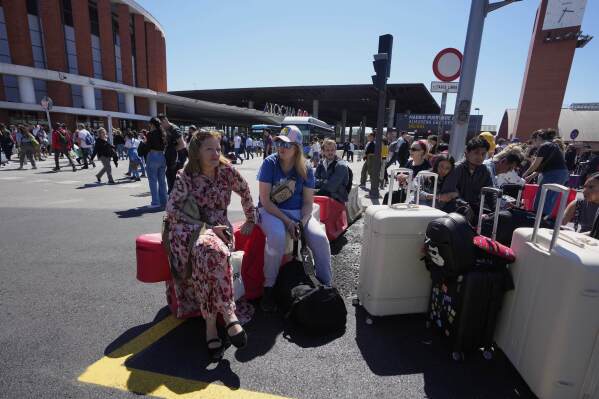 Pasajeros esperan fuera de la estación de Atocha durante un apagón nacional en Madrid, el lunes 28 de abril de 2025. (AP Foto/Manu Fernández)