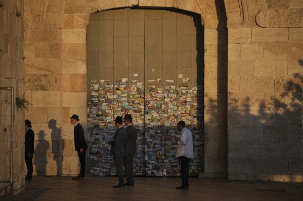 Ultra-Orthodox Jewish men pray next to the closed Jaffa Gate just outside Jerusalem's Old City following a ban on public gatherings imposed by Israel's Home Front Command after a military strike on Iran, Friday, June 13, 2025. (AP Photo/Ohad Zwigenberg)