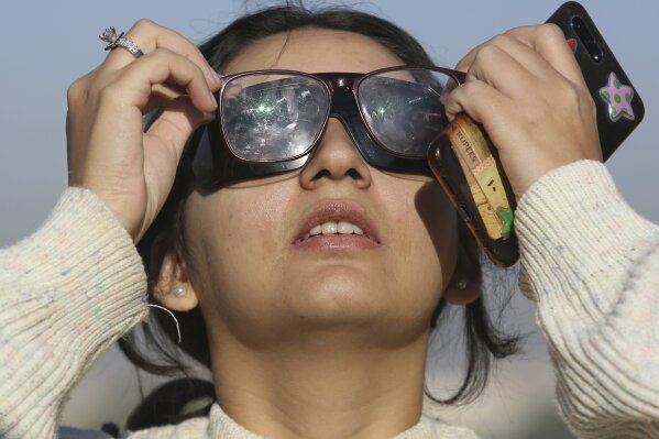 A student of Karachi University views the solar eclipse seen from Karachi, Pakistan, Thursday, Dec. 26, 2019. The last solar eclipse of 2019 was witnessed in Pakistan along with several other countries. (AP Photo/Fareed Khan)