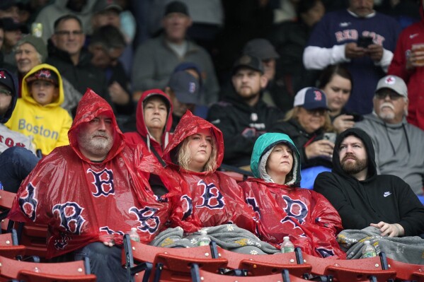 Fanáticos esperan bajo la lluvia la reanudación del juego entre los Medias Blancas de Chicago y los Medias Rojas de Boston, el domingo 24 de septiembre de 2023, en Boston. (AP Foto/Steven Senne)