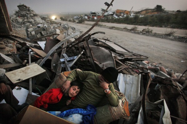 FILE - Palestinians from the Hamouda family rest in the rubble of their home following Israeli strikes intended for Hamas leaders, of east Jebaliya, Jan. 26, 2009. (AP Photo/Kevin Frayer, File)