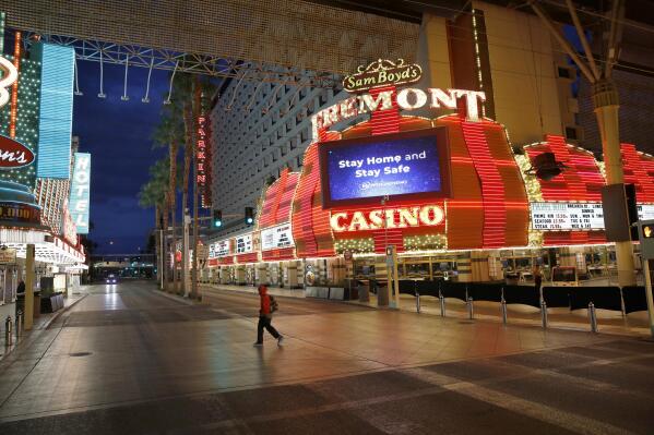 FILE - In this March 21, 2020, file photo, a man walks along a usually busy Fremont Street after casinos were ordered to shut down due to the coronavirus outbreak in Las Vegas. Federal figures show that about 24,000 out-of-work Nevada residents filed first-time unemployment claims. That pushes the percentage of people seeking jobless benefits to 31% since casinos and businesses shut down in mid-March due to the coronavirus pandemic. (AP Photo/John Locher, File)