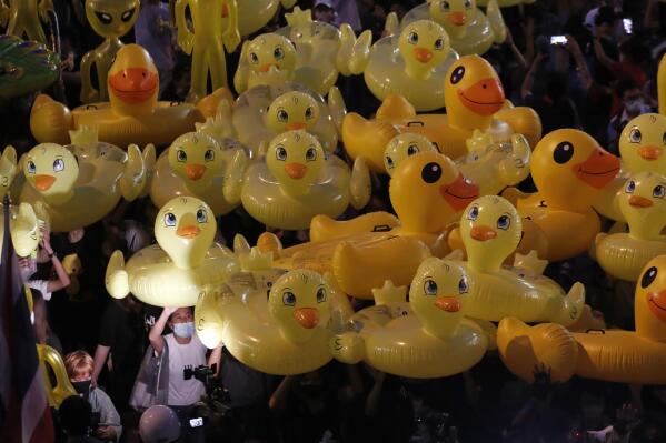 FILE - Inflatable yellow ducks, which have become good-humored symbols of resistance during anti-government rallies, are lifted over a crowd of protesters in Bangkok, Thailand, Nov. 27, 2020. A Thai man was sentenced to two years in prison on Tuesday, March 7, 2023 for selling calendars featuring satirical cartoons of yellow ducks that a court said mocked the country’s monarch, a legal aid group said. (AP Photo/Sakchai Lalit, File)
