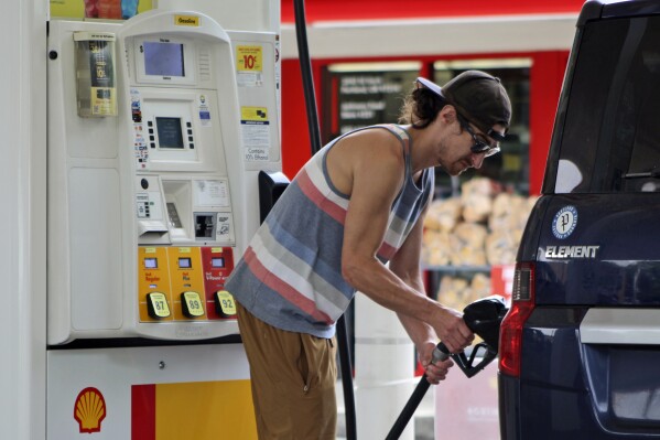 文件-俄勒冈州居民帕特里克·科芬（Patrick Coffin）于2023年8月4日在俄勒冈波特兰的一家加油站为自己的汽车加油。根据拜登政府于2024年6月7日（星期五）公布的新联邦法规，到2031年，美国售出的新车在实际行驶中平均每加仑汽油行驶约38英里，而今年约为29英里/加仑。美国总统乔·拜登（Joe Biden）设定了一个目标，即到2030年，美国售出的新车中有一半是电动的。（美联社照片/克莱尔·拉什档案）