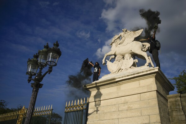 Youth light flares on Concorde square during a protest in Paris, France, Friday, June 30, 2023. French President Emmanuel Macron urged parents on Friday to keep teenagers at home and proposed restrictions on social media to quell rioting spreading across France over the fatal police shooting of a 17-year-old driver. (AP Photo/Lewis Joly)