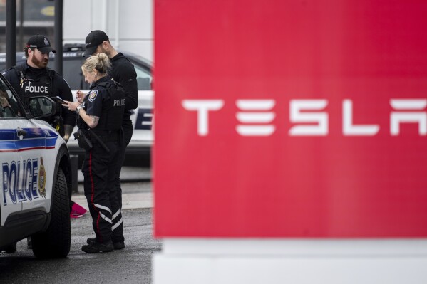 Officers from Ottawa Police Service (OPS) are seen at a Tesla Service and Showroom centre after it was damaged with pink spray paint in Ottawa, on Monday, March 31, 2025. (Spencer Colby/The Canadian Press via AP)