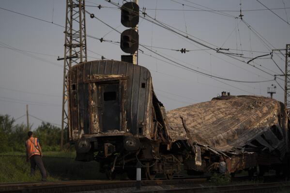 A railway worker looks at a heavily damaged train after a Russian attack on a train station Wednesday during Ukraine's Independence Day in the village Chaplyne, Ukraine, Thursday, Aug. 25, 2022. (AP Photo/Leo Correa)