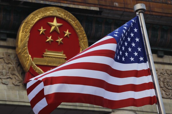 FILW - An American flag is flown next to the Chinese national emblem outside the Great Hall of the People in Beijing, Nov. 9, 2017. In the midst of two potentially world-changing conflicts, the U.S. is hoping to find at least a small measure of common ground with China as China's top diplomat visits Washington this week. (AP Photo/Andy Wong, File)
