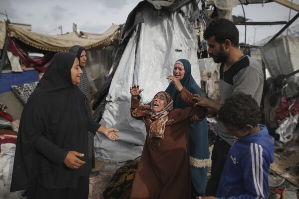 نازحون فلسطينيون يتفقدون خيامهم التي دمرها القصف الإسرائيلي، بجوار منشأة تابعة للأونروا غرب مدينة رفح، قطاع غزة، الثلاثاء، 28 مايو، 2024. (AP Photo/Jehad Alshrafi)